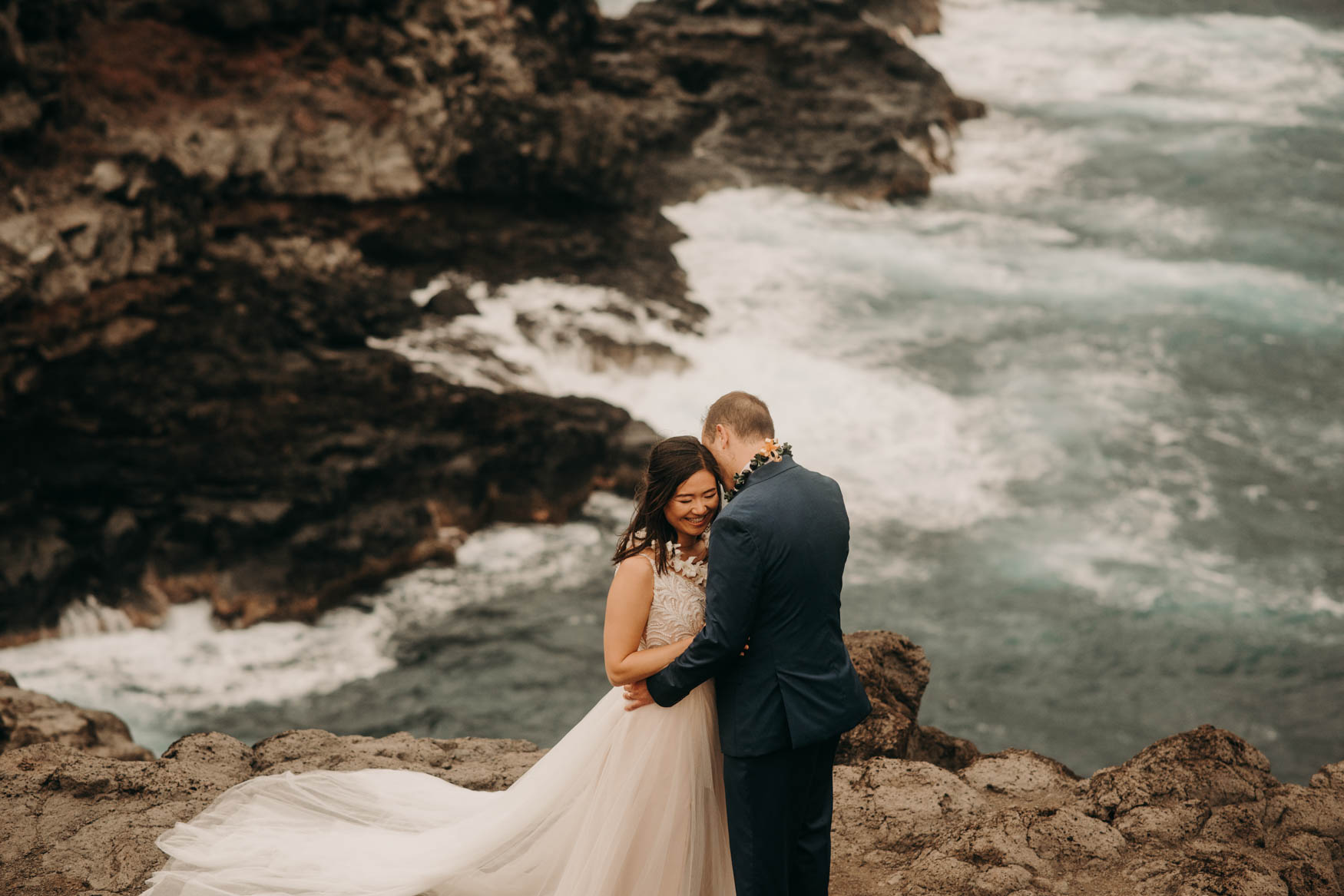 Andrew leans toward Alison's left ear, holding onto her waist. She holds onto his and smiles.